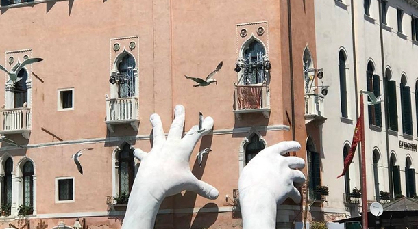 Gigantic stony hands rise from the Grand Canal in an environmental plea